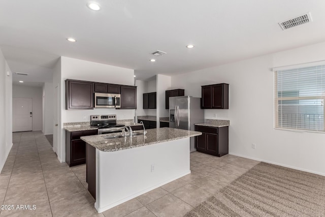 28259 N Chalcocite St, San Tan Valley, AZ 85143 - kitchen featuring appliances with stainless steel finishes, an island with sink, light tile patterned flooring, light stone counters, and dark brown cabinets