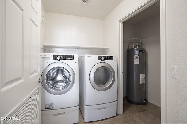 clothes washing area featuring water heater, visible vents, tile patterned flooring, washer and dryer, and laundry area