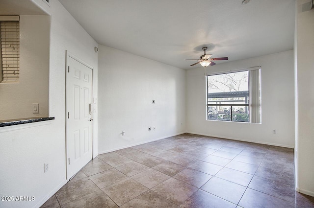 tiled spare room featuring a ceiling fan and baseboards