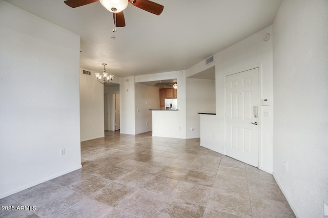 unfurnished living room with visible vents, baseboards, and ceiling fan with notable chandelier