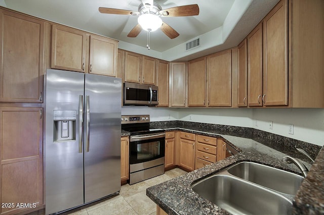 kitchen with visible vents, appliances with stainless steel finishes, dark stone countertops, a sink, and light tile patterned flooring