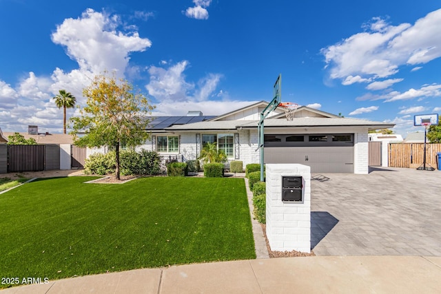 ranch-style home featuring a garage, roof mounted solar panels, a front yard, and a gate