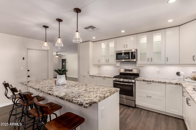 kitchen featuring visible vents, a center island, dark wood-style floors, and stainless steel appliances