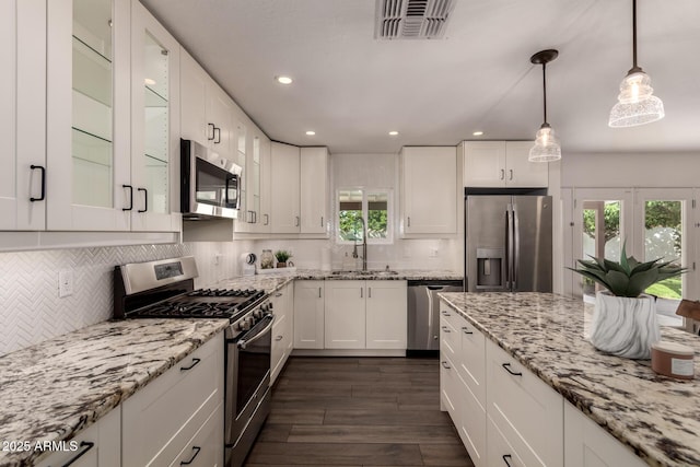 kitchen with a sink, white cabinets, appliances with stainless steel finishes, and dark wood-style floors