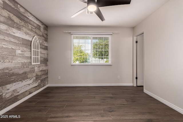 unfurnished room featuring visible vents, dark wood-style flooring, an accent wall, baseboards, and ceiling fan