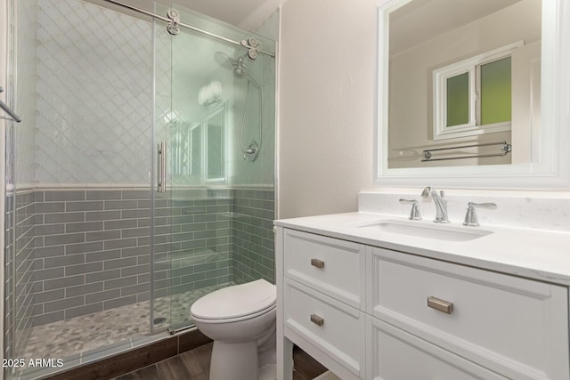 bathroom with vanity, a stall shower, toilet, and wood finished floors