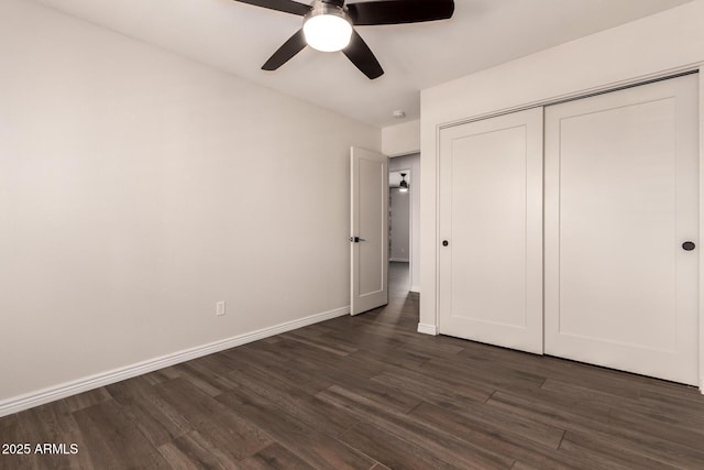 unfurnished bedroom featuring a ceiling fan, baseboards, dark wood finished floors, and a closet