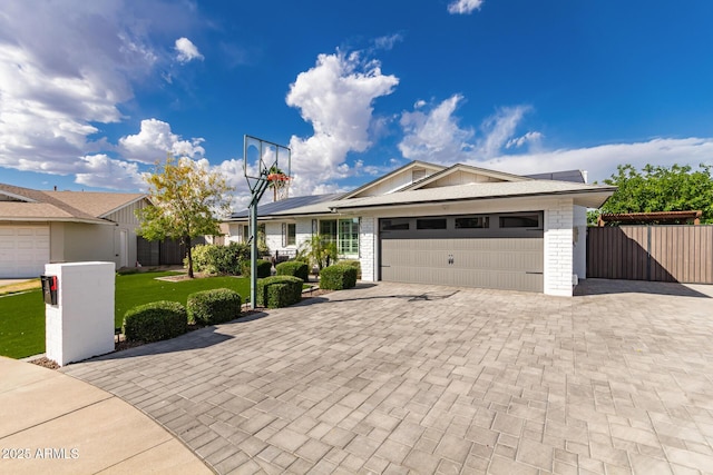 ranch-style home with decorative driveway, fence, a front lawn, and a garage