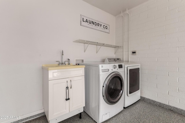 clothes washing area featuring washing machine and clothes dryer, baseboards, a sink, and cabinet space