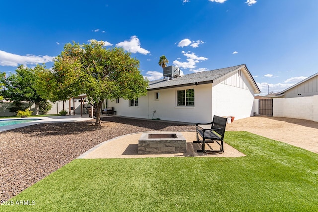 rear view of property featuring a patio, a fenced backyard, central AC unit, a lawn, and an outdoor fire pit