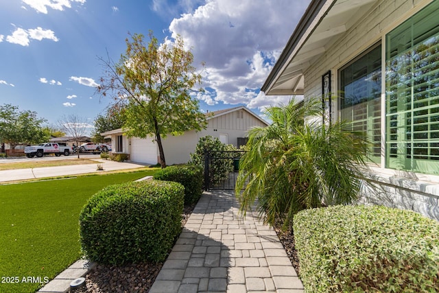 view of home's exterior with a lawn, a gate, an attached garage, and driveway