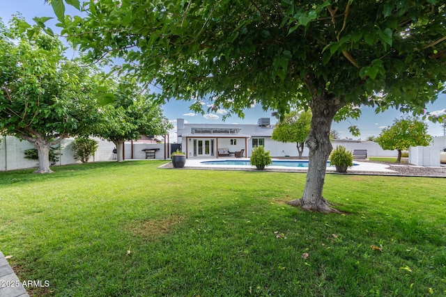 exterior space featuring a lawn, a fenced in pool, french doors, and a fenced backyard