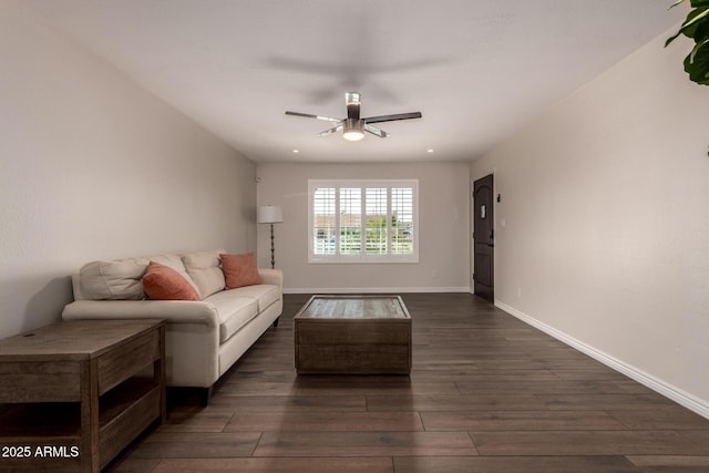 living area with baseboards, a ceiling fan, and dark wood finished floors