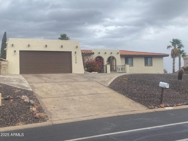 southwest-style home featuring fence, stucco siding, concrete driveway, a garage, and a tile roof