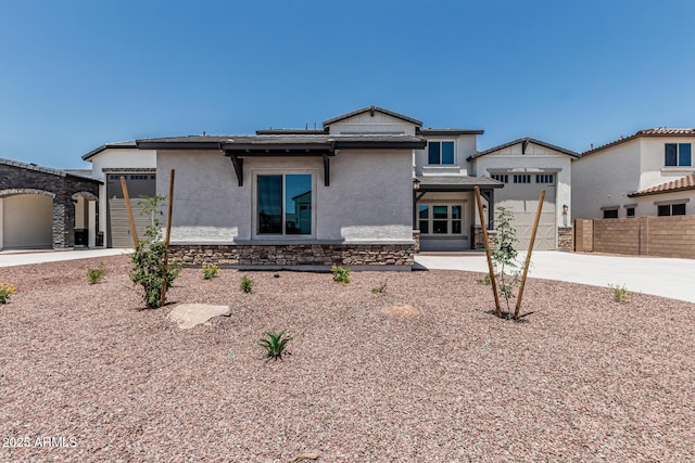 17322 W Puget Ave, Waddell, AZ 85355 - rear view of house featuring driveway, stucco siding, a garage, and stone siding