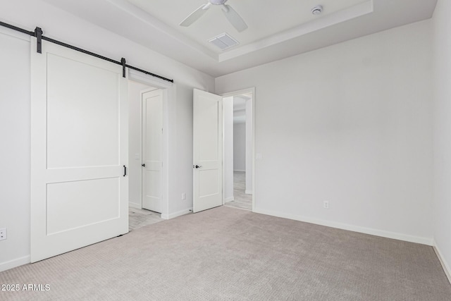 17322 W Puget Ave, Waddell, AZ 85355 - unfurnished bedroom featuring carpet, a barn door, a tray ceiling, and a ceiling fan