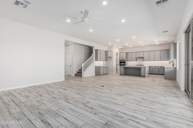 17322 W Puget Ave, Waddell, AZ 85355 - unfurnished living room featuring a ceiling fan, light wood-style flooring, stairs, and recessed lighting