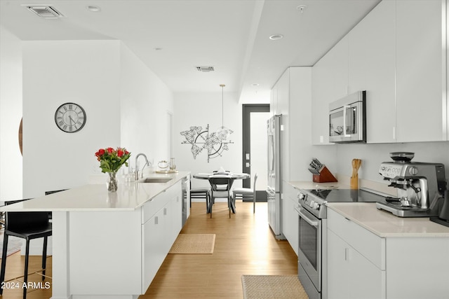 kitchen with white cabinetry, appliances with stainless steel finishes, sink, and decorative light fixtures