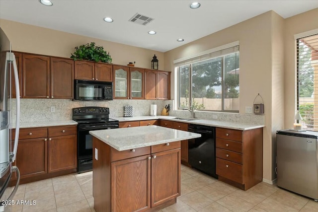 kitchen featuring light stone counters, backsplash, sink, and black appliances