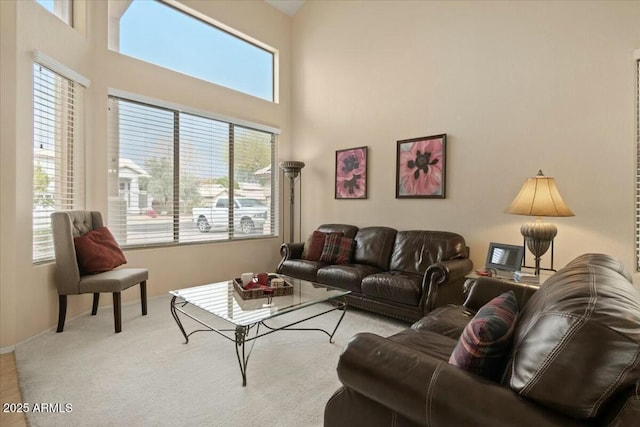 living room featuring a towering ceiling and light colored carpet