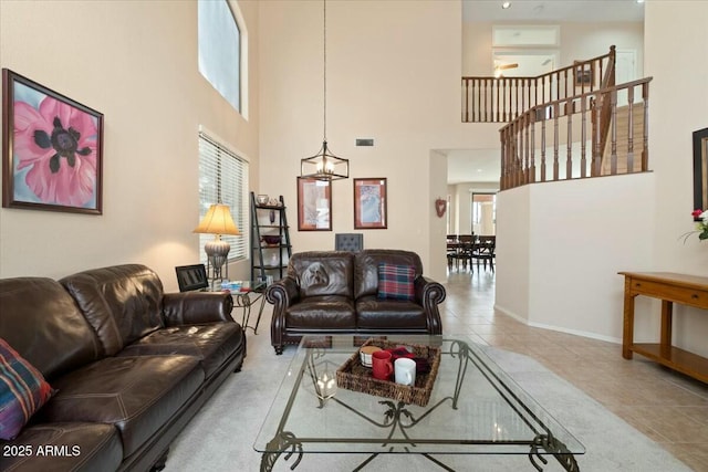 living room with a towering ceiling, tile patterned floors, and a chandelier