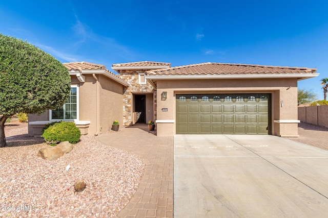 view of front of property featuring an attached garage, a tile roof, stone siding, concrete driveway, and stucco siding