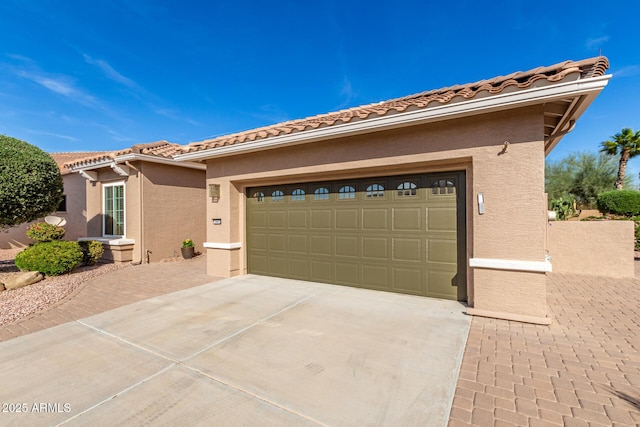 view of front facade with concrete driveway, a tile roof, an attached garage, and stucco siding