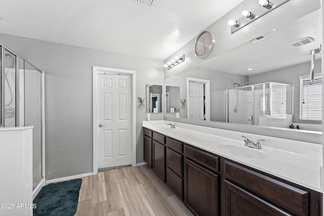 bathroom with a stall shower, visible vents, a sink, and wood finished floors