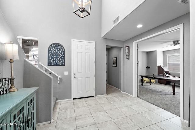 foyer featuring light tile patterned floors, visible vents, a ceiling fan, light carpet, and baseboards