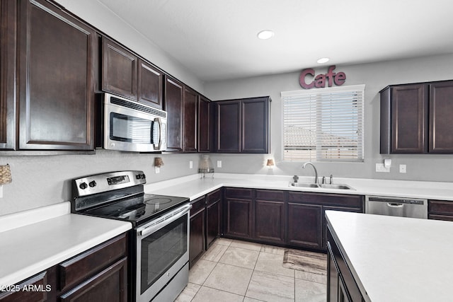 kitchen featuring recessed lighting, light countertops, appliances with stainless steel finishes, a sink, and dark brown cabinets