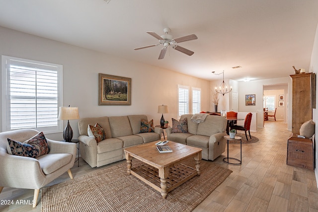 living room featuring ceiling fan with notable chandelier and light wood-type flooring