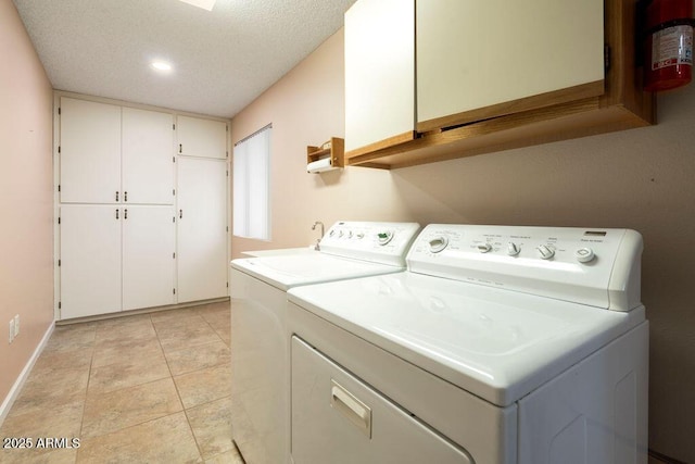 laundry area featuring light tile patterned flooring, cabinets, a textured ceiling, and washing machine and dryer