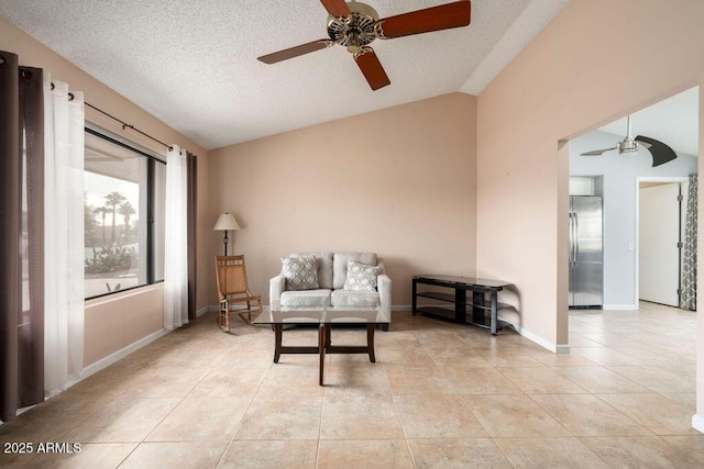 sitting room featuring a textured ceiling, ceiling fan, light tile patterned floors, and vaulted ceiling