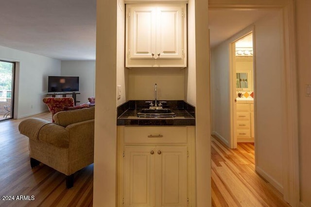 bar with white cabinetry, sink, and light hardwood / wood-style flooring