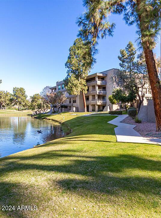 view of property's community featuring a lawn and a water view