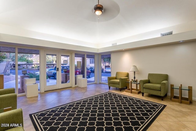 tiled living room with ceiling fan and french doors