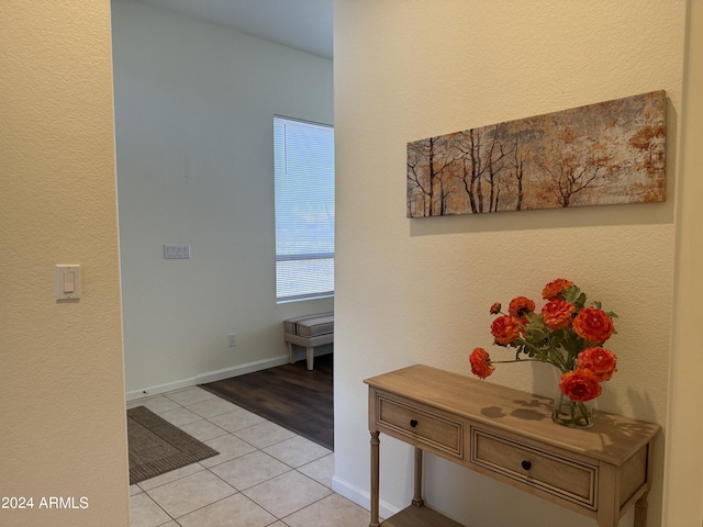 hall featuring light tile patterned floors and baseboards