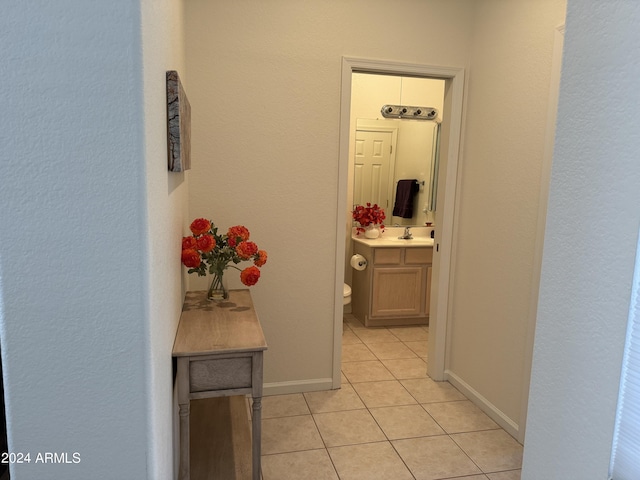 hall with a sink, baseboards, and light tile patterned flooring