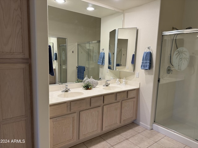 full bath with tile patterned floors, double vanity, a stall shower, and a sink