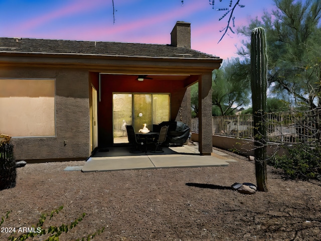 exterior space featuring stucco siding, a ceiling fan, a patio, fence, and a chimney