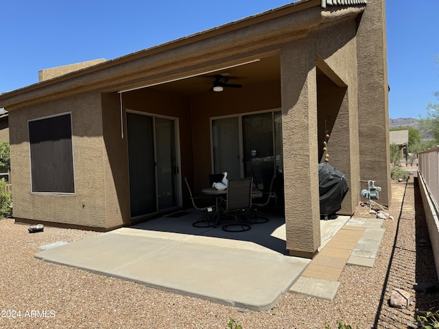 back of property with stucco siding, ceiling fan, a patio, and fence