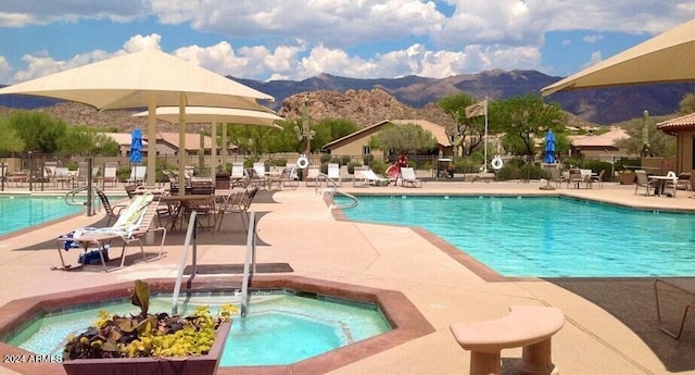 community pool with a patio area, fence, and a mountain view