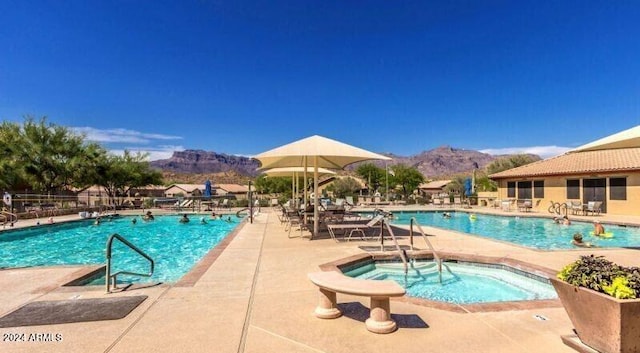 pool featuring a patio area, a mountain view, and a hot tub