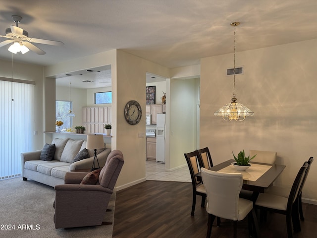 dining space with visible vents, ceiling fan with notable chandelier, baseboards, and wood finished floors