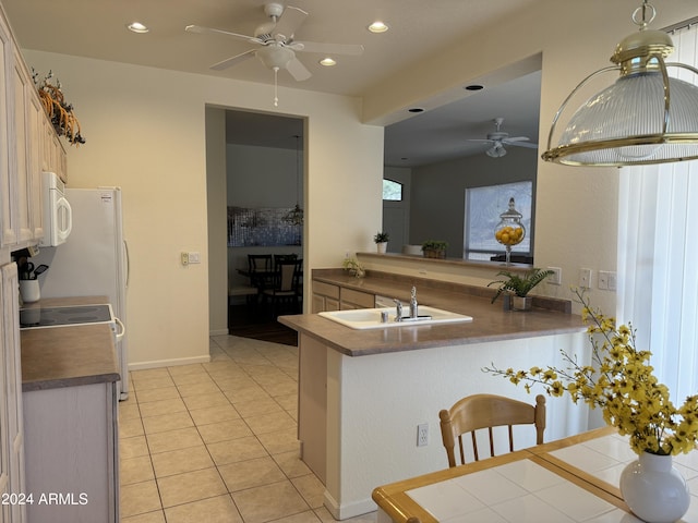 kitchen featuring white microwave, light tile patterned floors, recessed lighting, a peninsula, and a sink