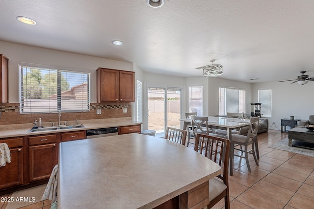 kitchen featuring light tile patterned floors, tasteful backsplash, a sink, and dishwasher