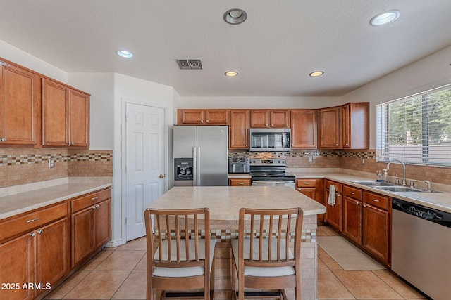 kitchen featuring decorative backsplash, stainless steel appliances, brown cabinets, and a sink