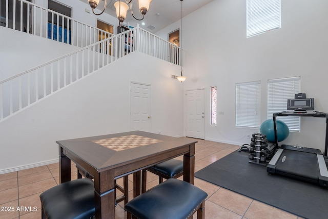 dining area featuring a notable chandelier, stairway, baseboards, tile patterned flooring, and a towering ceiling