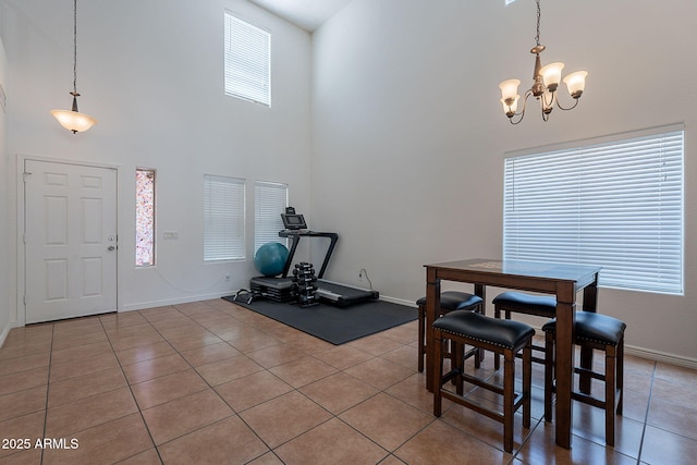 interior space with a towering ceiling, a notable chandelier, baseboards, and light tile patterned floors