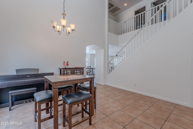 dining space featuring a high ceiling, visible vents, arched walkways, a chandelier, and light tile patterned flooring